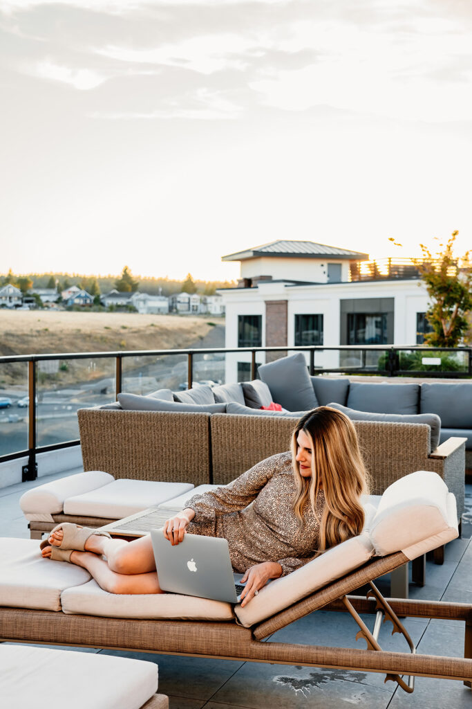a life coach sitting on a pool chair working on her computer showing others they can do their business anywhere