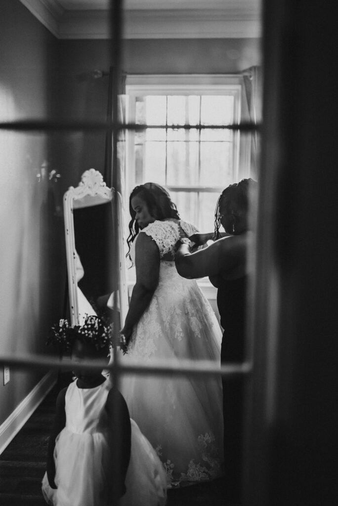 Mom helping daughter zipping up her wedding dress
