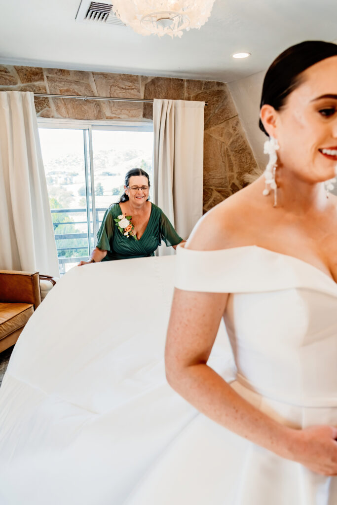 mom fluffing out brides train on her wedding day